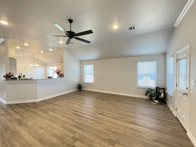 unfurnished living room featuring visible vents, vaulted ceiling, wood finished floors, baseboards, and ceiling fan with notable chandelier