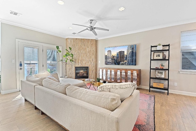 living room with light wood-type flooring, visible vents, ornamental molding, a large fireplace, and baseboards