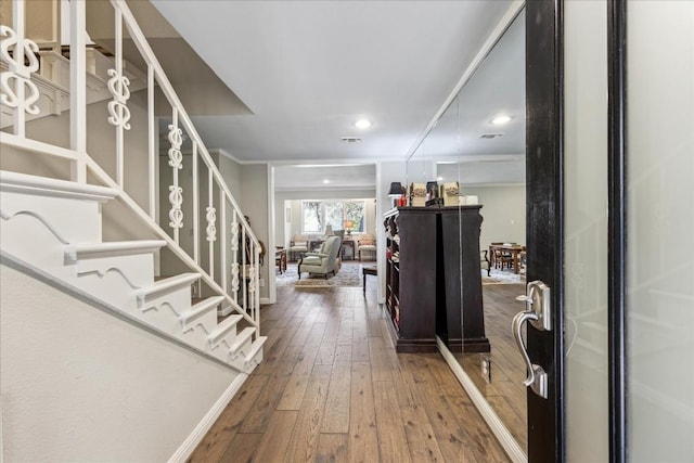 foyer entrance featuring hardwood / wood-style flooring, stairway, and visible vents