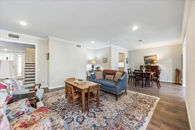 living area with ornamental molding, visible vents, baseboards, and wood finished floors