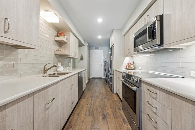 kitchen featuring dark wood-style floors, stainless steel appliances, light countertops, light brown cabinetry, and a sink