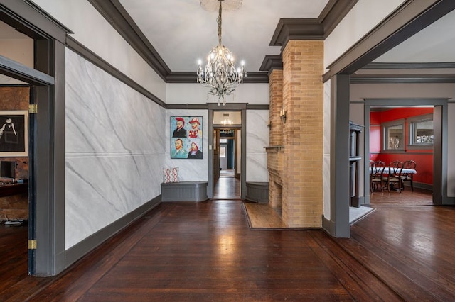 interior space featuring hardwood / wood-style flooring, baseboards, ornamental molding, an inviting chandelier, and ornate columns