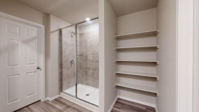 full bath featuring wood finished floors, a shower stall, and baseboards