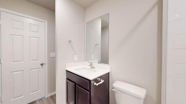 bathroom with wood finished floors, vanity, and toilet