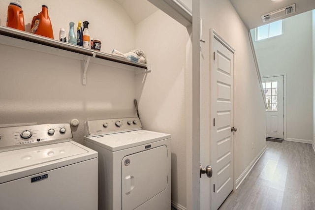 clothes washing area featuring light wood-style floors, plenty of natural light, visible vents, and independent washer and dryer