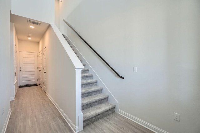 staircase with visible vents, baseboards, and wood finished floors