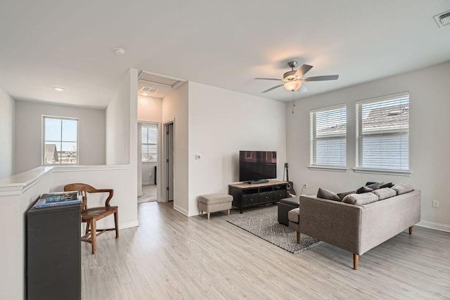 living room with light wood-style floors, visible vents, ceiling fan, and baseboards