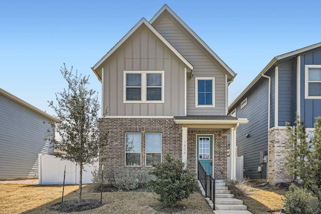 view of front of home with board and batten siding, brick siding, and fence