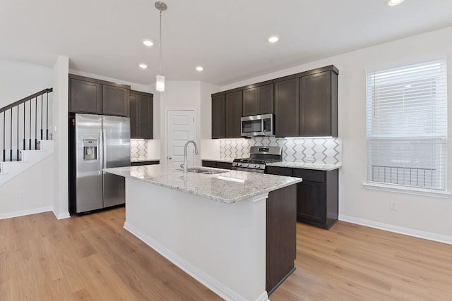 kitchen with dark brown cabinetry, light wood-style flooring, stainless steel appliances, and a sink