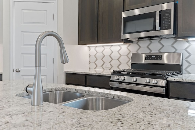 kitchen featuring appliances with stainless steel finishes, a sink, dark brown cabinetry, and tasteful backsplash