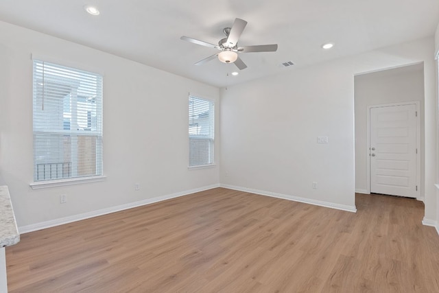 empty room featuring light wood finished floors, visible vents, and baseboards