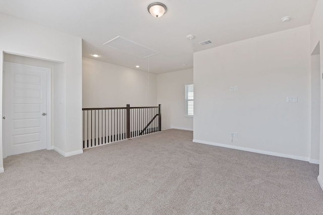 empty room with attic access, baseboards, visible vents, and carpet flooring