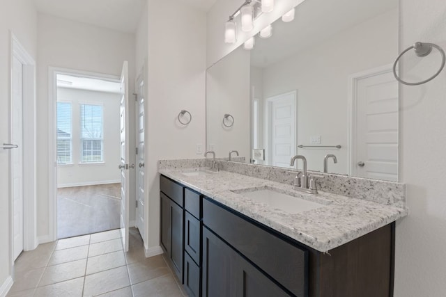 full bath with double vanity, tile patterned flooring, baseboards, and a sink