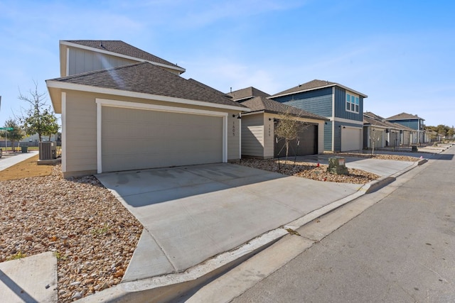 view of front of property with cooling unit, concrete driveway, roof with shingles, and an attached garage