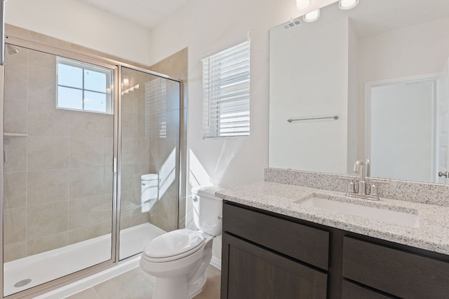 bathroom with a stall shower, vanity, toilet, and tile patterned floors