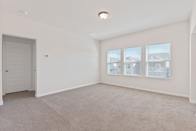 carpeted spare room featuring visible vents and baseboards