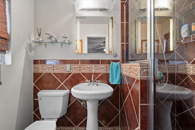 bathroom featuring toilet, a wainscoted wall, and tile walls