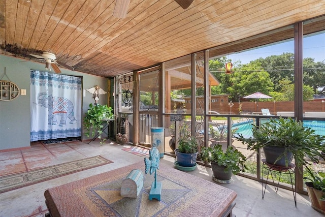 unfurnished sunroom featuring wooden ceiling, ceiling fan, and a wealth of natural light