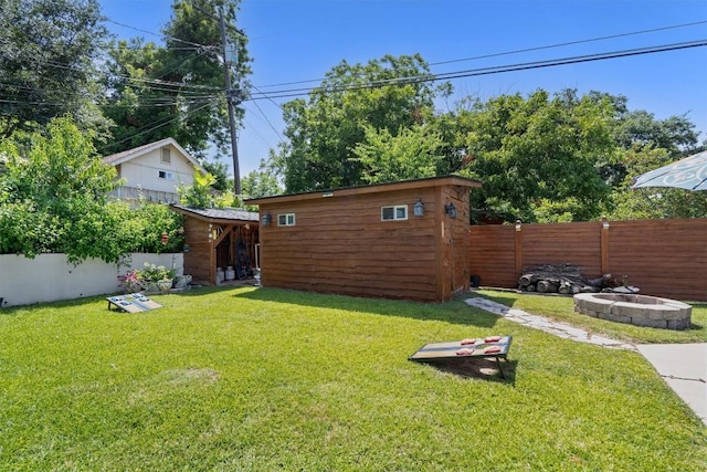 view of yard featuring a storage shed, an outdoor fire pit, a fenced backyard, and an outbuilding