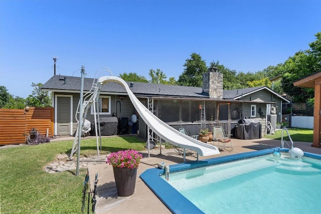 back of property with a fenced in pool, a sunroom, fence, a yard, and a patio area