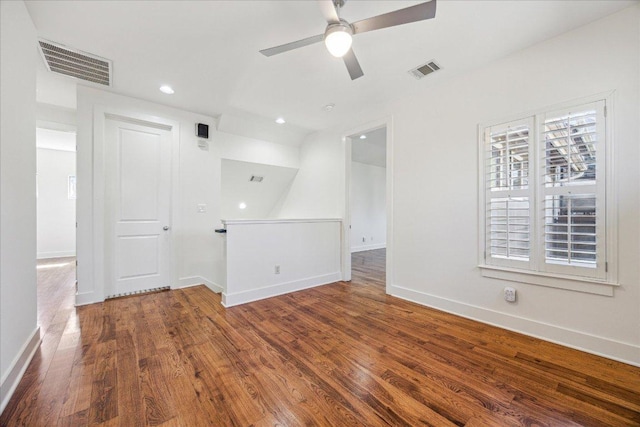 spare room with wood finished floors, visible vents, and baseboards