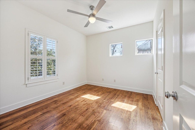 unfurnished room with visible vents, plenty of natural light, baseboards, and wood finished floors