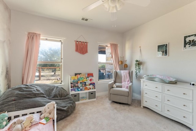 bedroom with a ceiling fan, visible vents, light carpet, and multiple windows