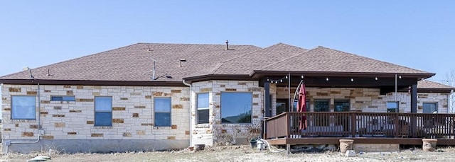 exterior space featuring stone siding and roof with shingles