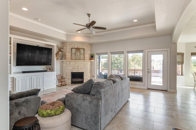 living room with a fireplace, a tray ceiling, and ornamental molding