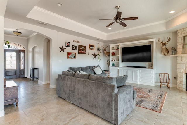 living room with ornamental molding, a tray ceiling, visible vents, and arched walkways