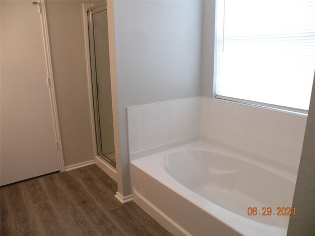 bathroom with a stall shower, wood finished floors, and a bath