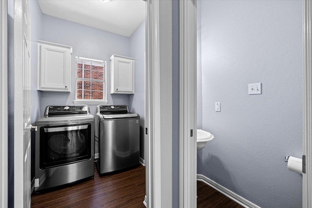 laundry area with cabinet space, a textured wall, dark wood-type flooring, independent washer and dryer, and baseboards