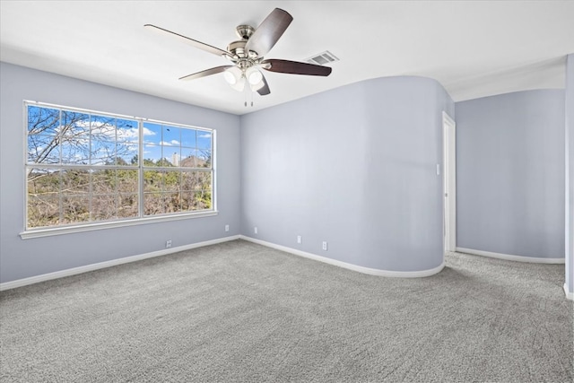 carpeted empty room featuring a ceiling fan, visible vents, and baseboards