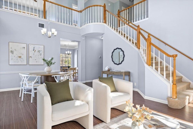 living room with wood finished floors, visible vents, stairway, and an inviting chandelier