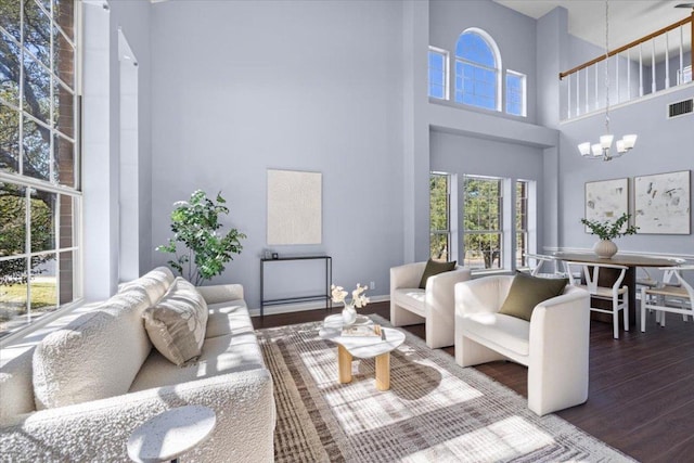 living room featuring baseboards, a notable chandelier, visible vents, and wood finished floors