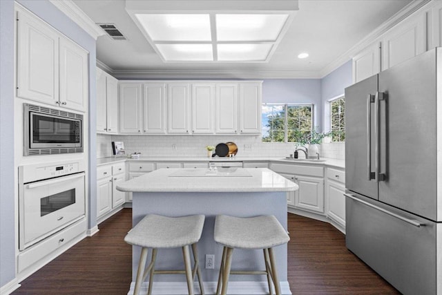 kitchen with a kitchen breakfast bar, stainless steel appliances, white cabinetry, and crown molding