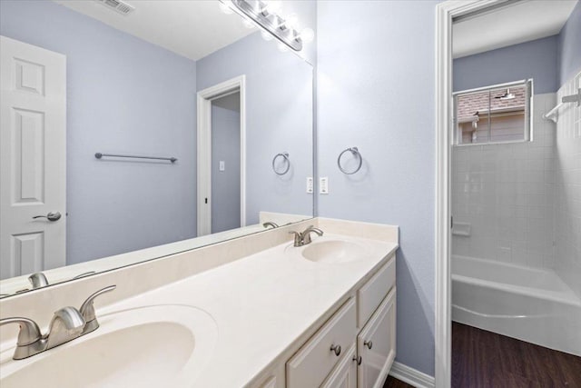 bathroom featuring double vanity, baseboards, a sink, and wood finished floors