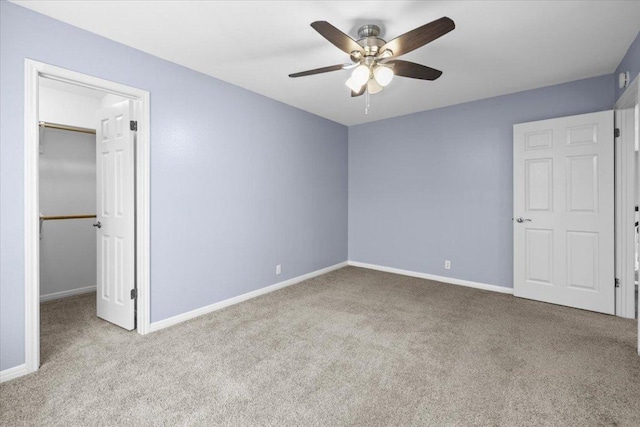 unfurnished bedroom with carpet flooring, a walk in closet, and baseboards