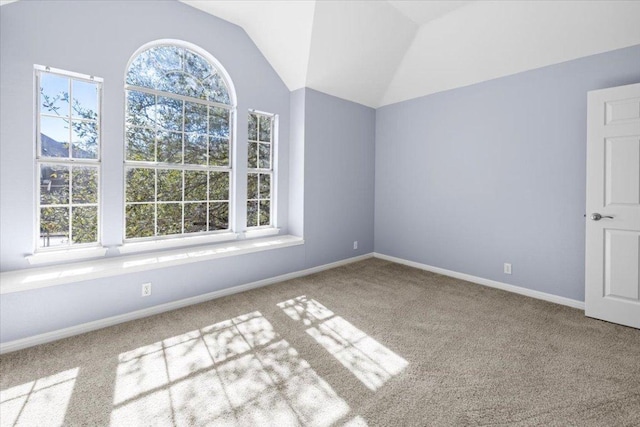 spare room featuring carpet floors, vaulted ceiling, and baseboards