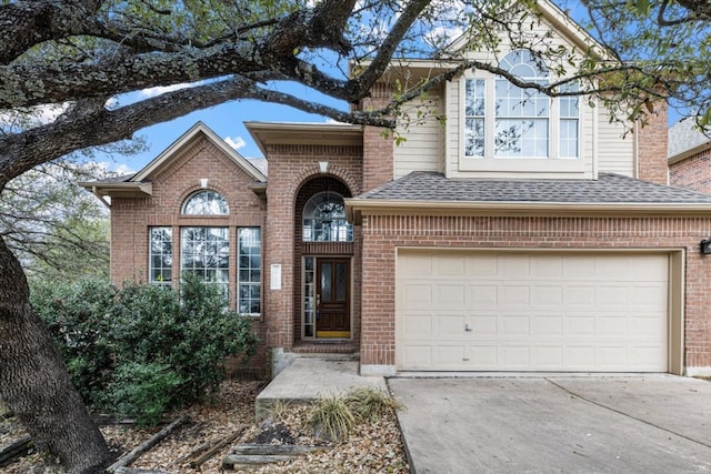 traditional-style home with a garage, driveway, a shingled roof, and brick siding