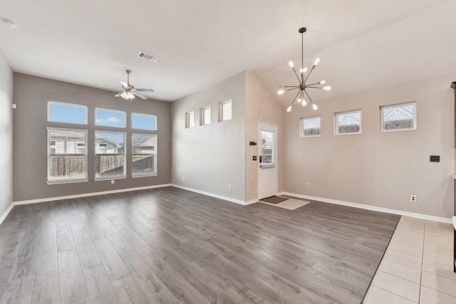 unfurnished living room with visible vents, ceiling fan with notable chandelier, baseboards, and wood finished floors