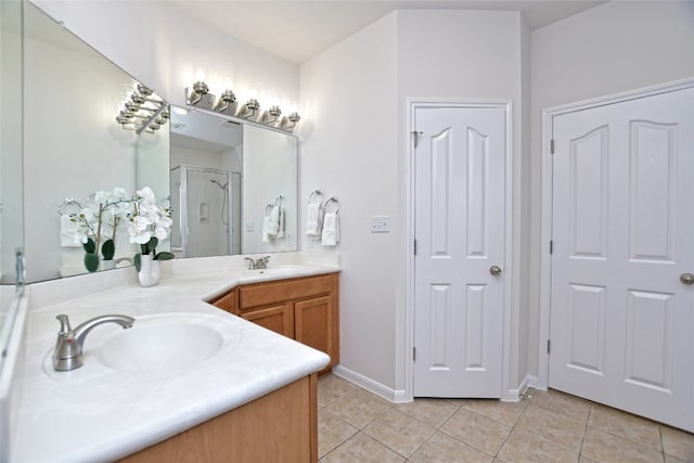 bathroom featuring double vanity, a stall shower, a sink, and tile patterned floors