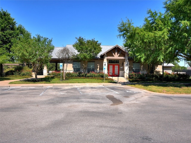 view of front facade with uncovered parking, french doors, and a front yard