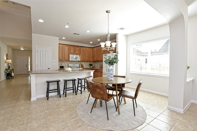 dining space with light tile patterned floors, baseboards, visible vents, and a notable chandelier