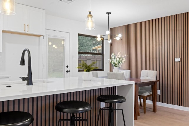 kitchen featuring pendant lighting, white cabinetry, light wood-style flooring, and a kitchen bar