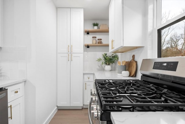 kitchen featuring tasteful backsplash, stainless steel appliances, light wood-type flooring, white cabinetry, and open shelves