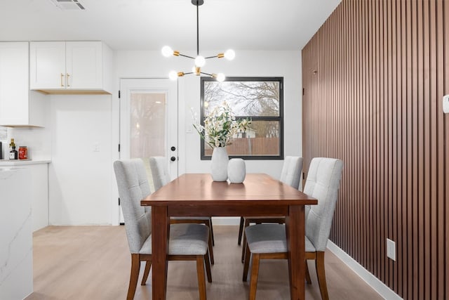 dining room with light wood-type flooring, visible vents, and an inviting chandelier