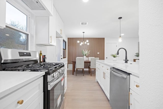 kitchen featuring visible vents, stainless steel appliances, light countertops, light wood-style floors, and white cabinetry