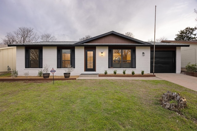 view of front of property with an attached garage, brick siding, driveway, and a front lawn