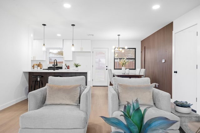 living area featuring baseboards, light wood finished floors, a notable chandelier, and recessed lighting